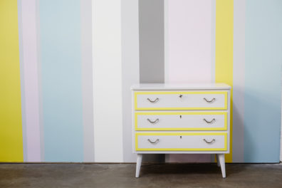 illustrasjonsbilde liten hvit og gul kommode ved stripete vegg