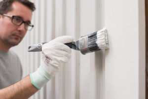 Malingen etterstrykes med en pensel for å sikre at kledningen får en jevn malingsfilm