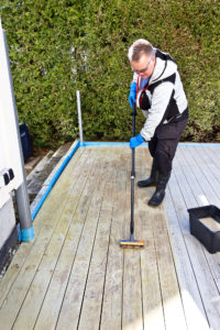 Mann skrubber terrasse med kost