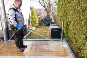 Mann spyler terrasse med hageslange